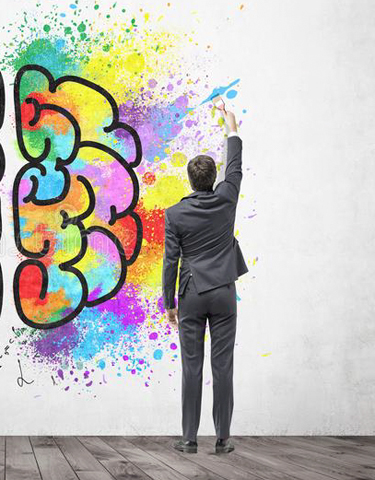 Mental sundhed og anti-stress: ryggen af en mand der tegner grafitti på en stor hvid væg