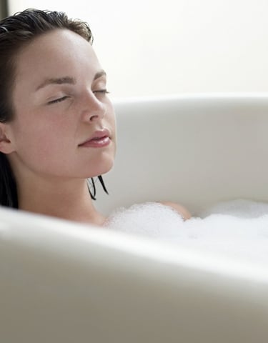 Mental sundhed og anti-stress: kvinde med lukkede øjne i et badekar med bobler